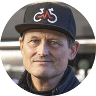 Porträt des Ladeninhabers mit schwarzer Kappe mit Fahrradlogo.