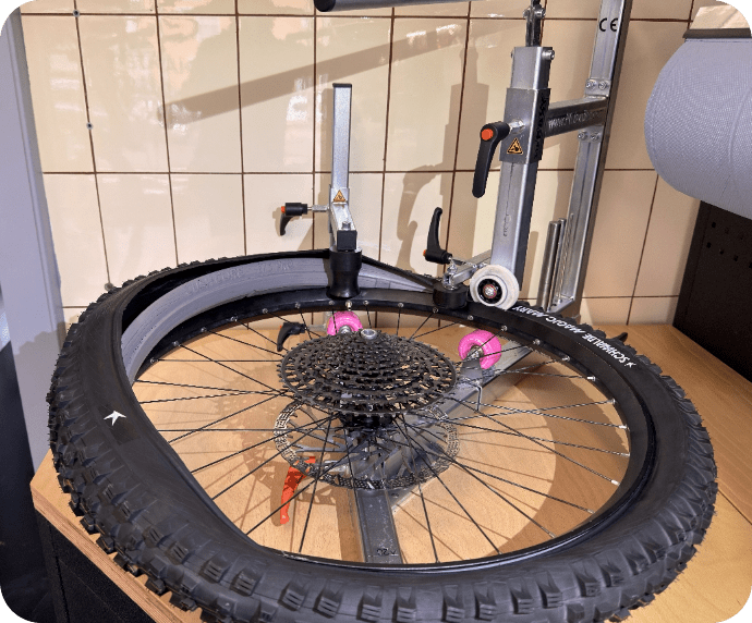 Fahrradmechaniker richtet ein Laufrad in der Werkstatt aus.